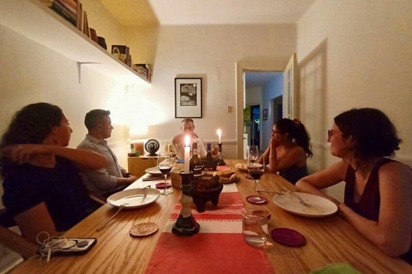 A group of people dining at a wooden table with candles, plates, and glasses. 5