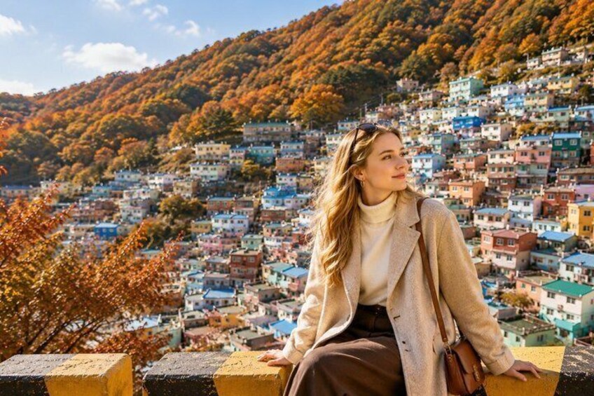 A person sitting on a ledge overlooking a hillside village with colorful houses. 1