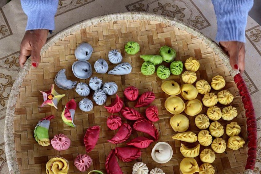 Un plateau tressé contenant des raviolis de différentes couleurs et de formes variées. 4