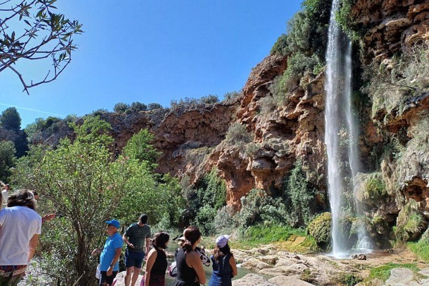 Une cascade, des falaises rocheuses et un groupe de personnes qui l’observent. 3