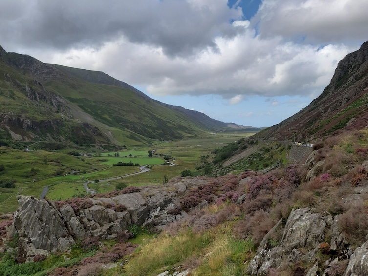 A valley with a river, rocky terrain, and distant mountains under a cloudy sky. 3