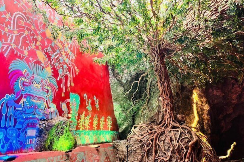 A tree with exposed roots against a colorful mural. 2