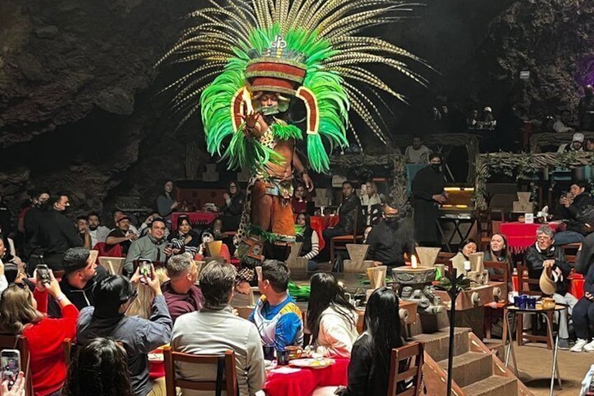 A cultural performance with a performer in traditional attire and a large feathered headdress. 3