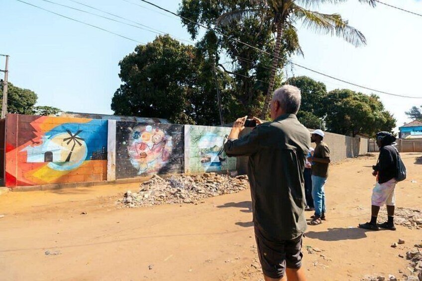 A man taking a photo of a colorful mural on a wall. 4