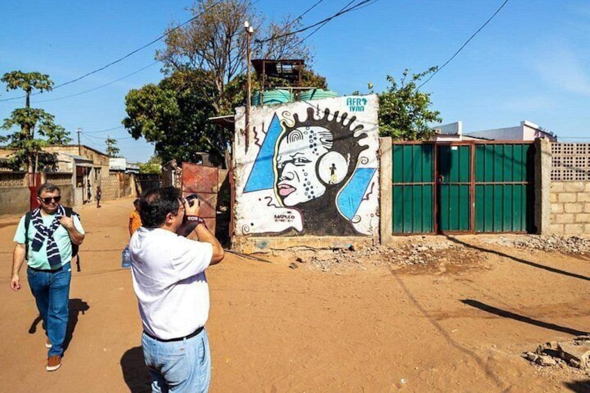A mural on a wall, a person taking a photo, and a building with a green door. 5