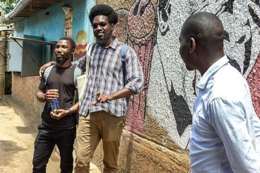 Three men standing in front of a mural with a building in the background. 2