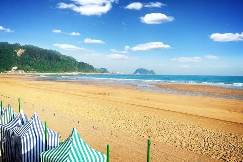 A beach with tents, a sandy shore, and a distant island. 4