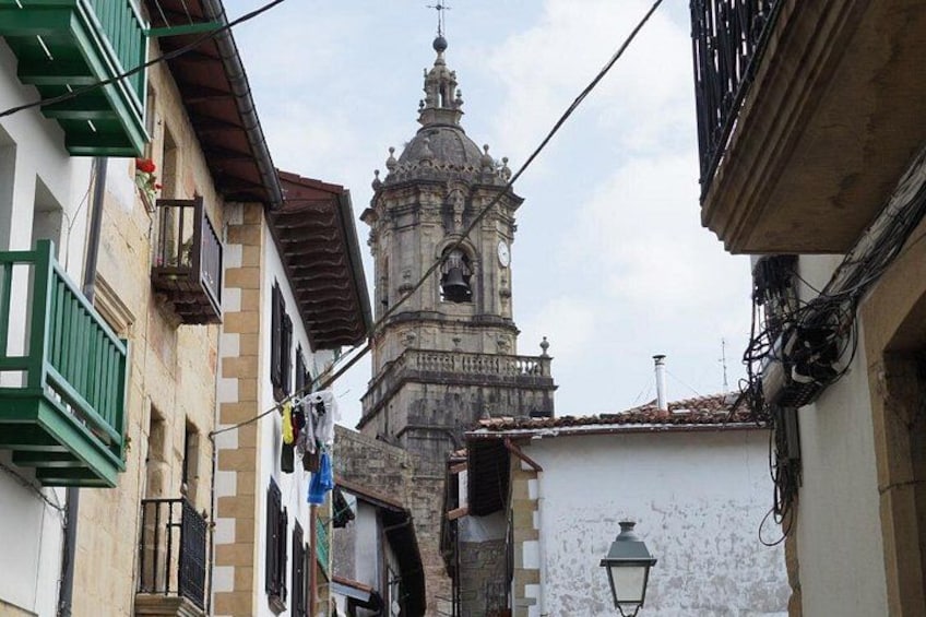 A narrow street with buildings, a clock tower, and a hanging lantern. 3