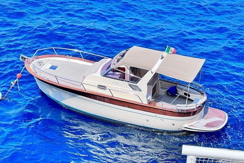 Un piccolo motoscafo con cabina e tendalino, che galleggia su acque blu. 2