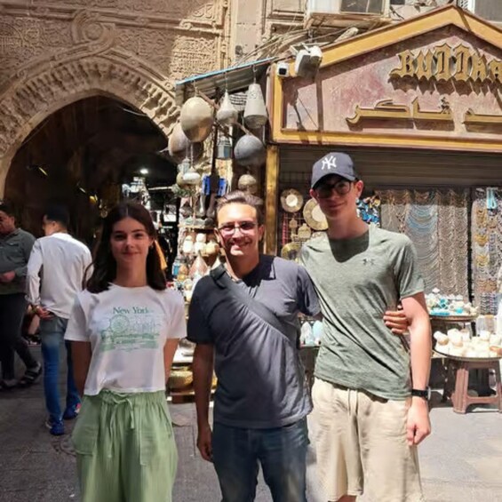 Un grupo de personas frente a una tienda con arcos decorativos y luces colgantes. 3