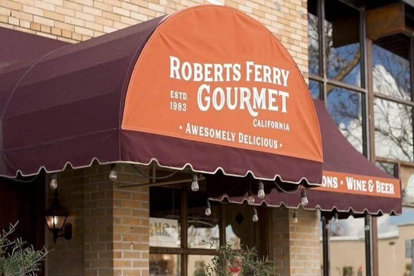 En restaurant kaldet Roberts Ferry Gourmet med en mørklilla markise og et skilt, der angiver, at der serveres vin og øl. 5