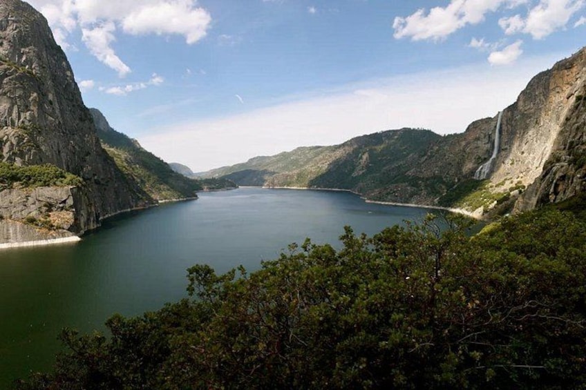 A lake surrounded by steep cliffs, a clear sky, and dense forest. 2