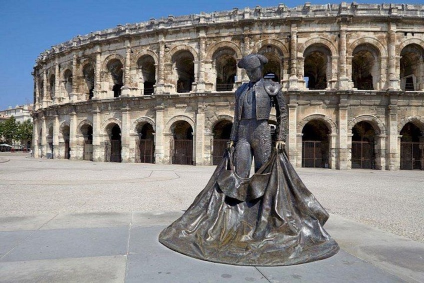 A statue in front of a historic building with arches. 1
