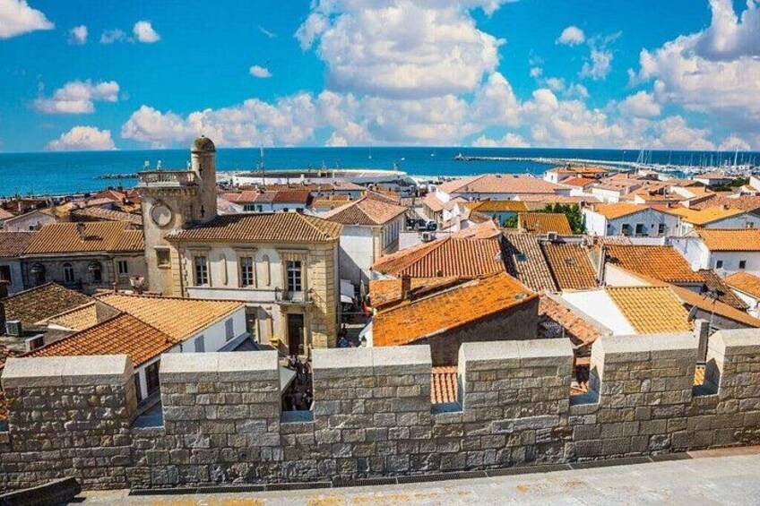 A coastal town with historic buildings, a stone wall, and a clear blue sky. 3