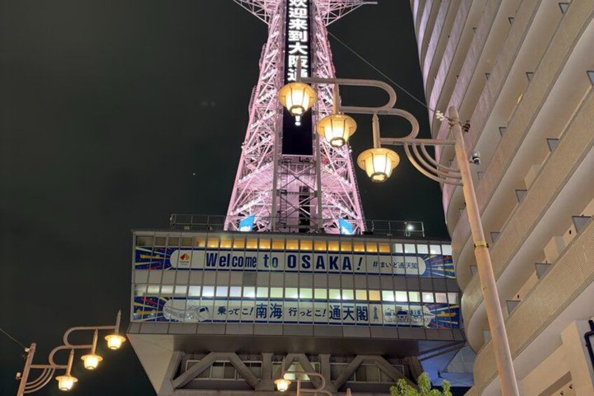 A brightly lit tower with a sign that reads 'Welcome to Osaka!' 5