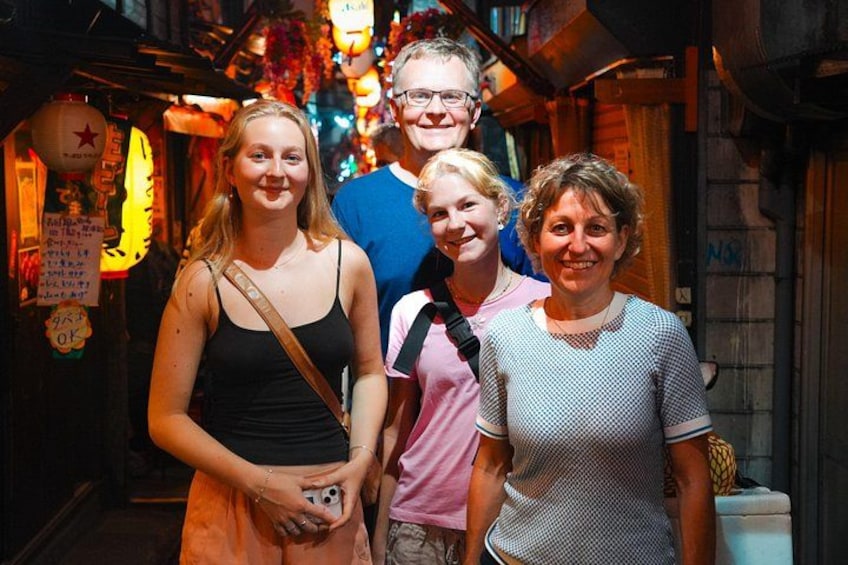 A narrow alley with wooden walls, a person in a black tank top, and another in a pink shirt. 2