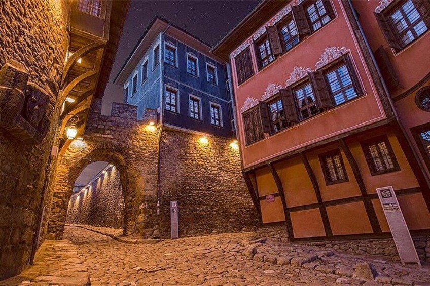 Un estrecho callejón con edificios de piedra, un arco de piedra y ventanas iluminadas. 5