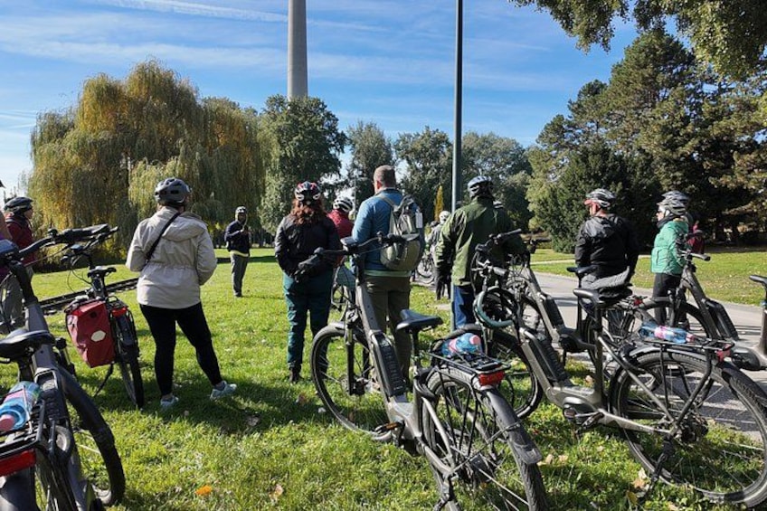 A group of cyclists gathered in a park with bicycles and trees in the background. 1