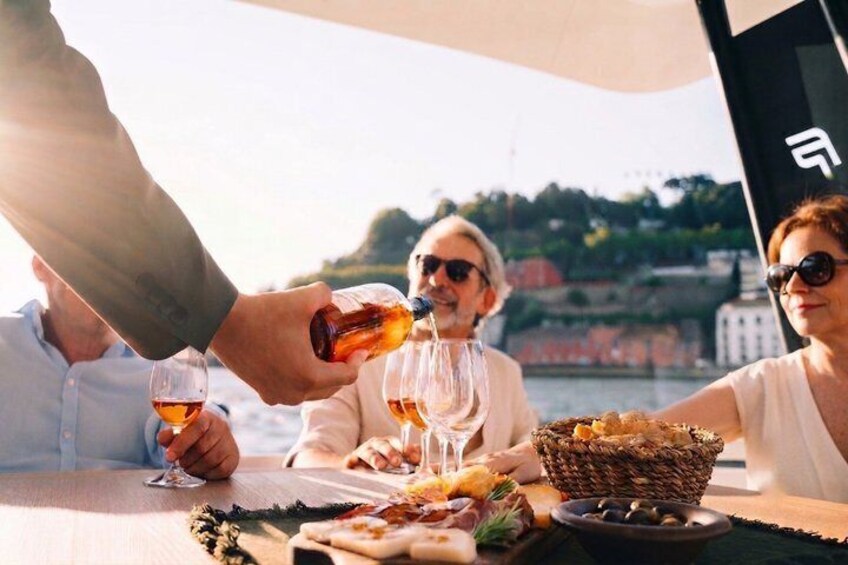 A group of people toasting with drinks at a table with food and a basket. 1