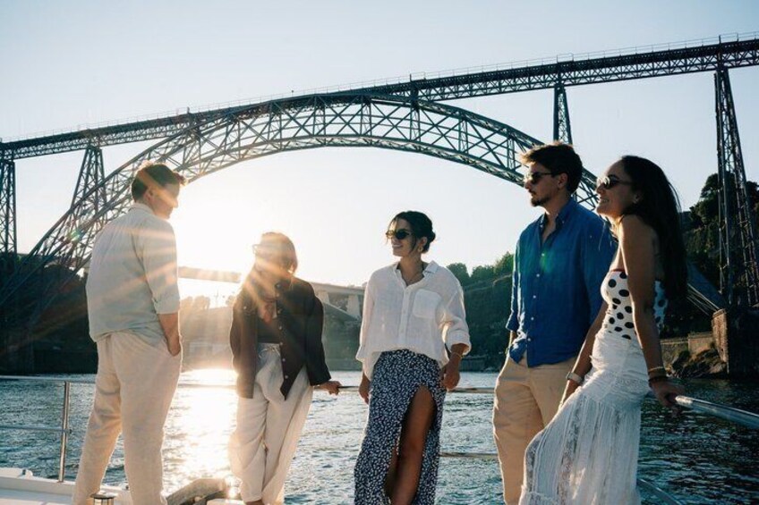 A group of people standing on a boat near a bridge. 4