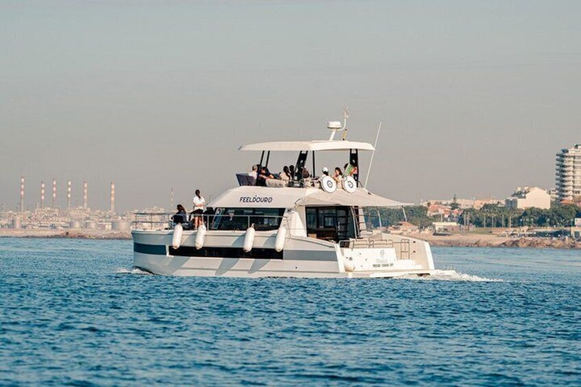 A large boat named FEELDOURO on the water with a cityscape in the background. 2