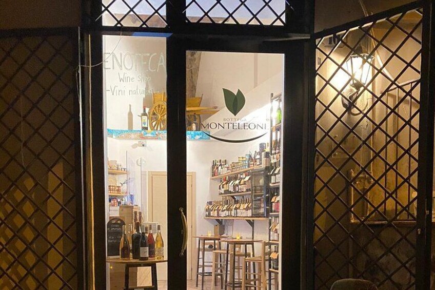 Una tienda de vinos con un letrero que dice 'Bottega Monteleoni' y una exhibición de botellas de vino. 2