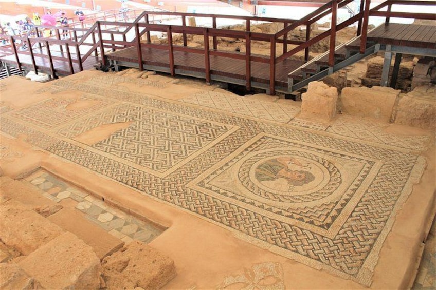 An archaeological site with ancient mosaic floors and a wooden walkway. 3
