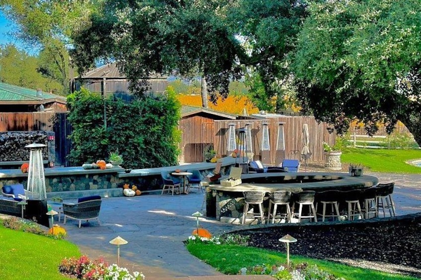 A patio area with outdoor seating, a small stage, and a garden with flowers and trees. 4