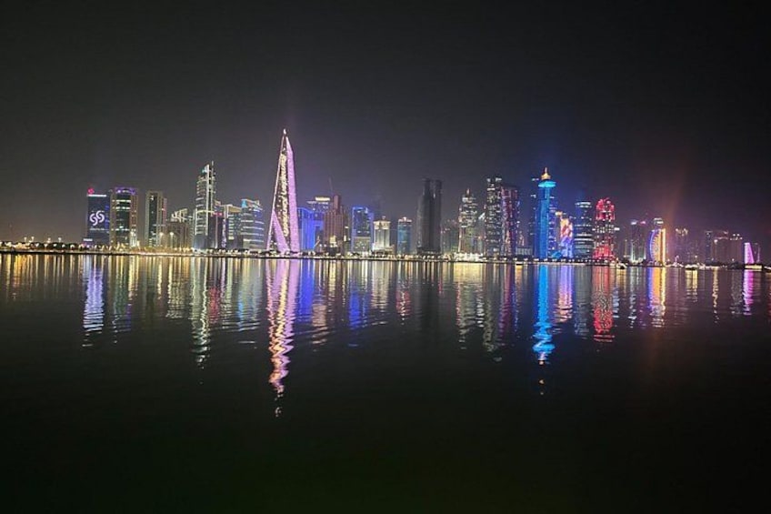 A nighttime city skyline with illuminated buildings reflected in a body of water. 4