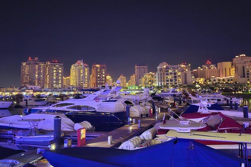 A marina at night with boats docked and a city skyline in the background. 2