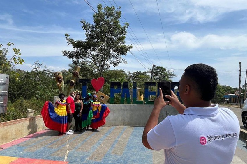 Un grupo de personas con vestidos coloridos de pie en un escenario con un cartel que dice 'LOVE' y un símbolo de corazón. 5