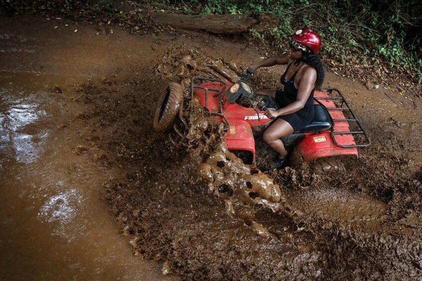 A person riding a red ATV through a muddy terrain. 1