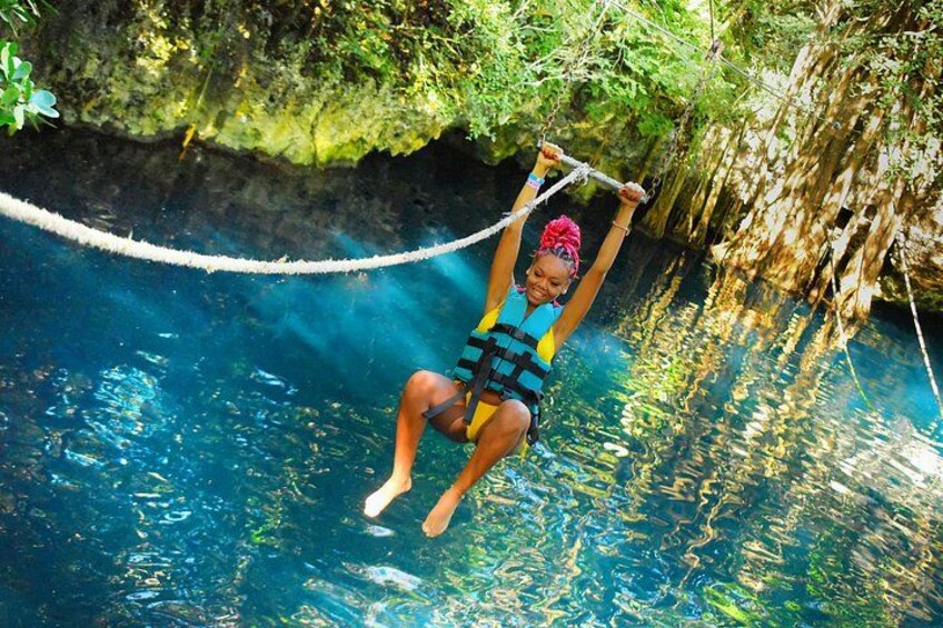 A person swinging on a rope over a body of water surrounded by greenery. 3