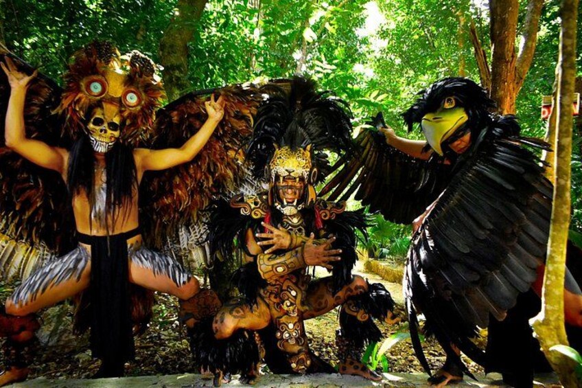 A group of people in elaborate costumes with feathers and masks in a forest setting. 5