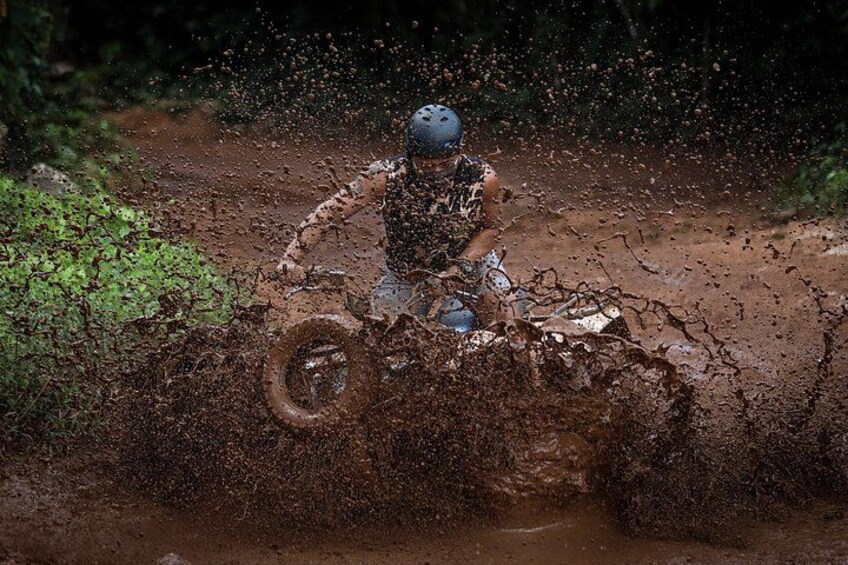 A person riding a motorcycle through a muddy terrain, splashing mud. 2