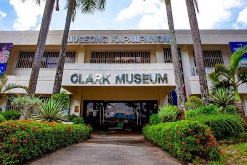 Indgangen til Clark Museet med en sti, der fører til bygningen, omgivet af palmer og velplejede grønne områder. 2