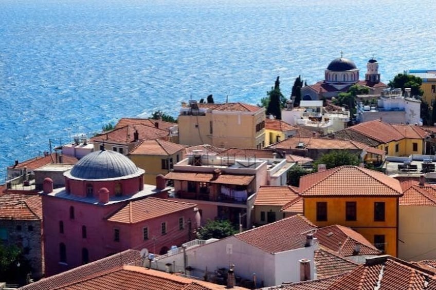A coastal town with terracotta-roofed buildings, a prominent dome, and a clear blue sea. 4