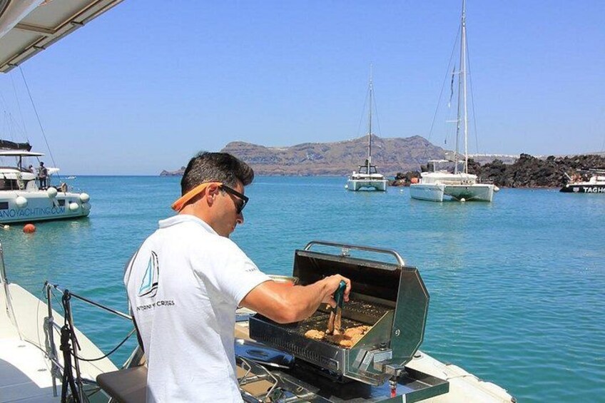 A man grilling on a boat with sailboats in the background. 3
