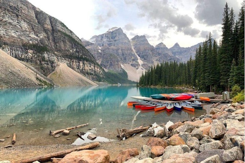 Un lac paisible, entouré de montagnes, avec plusieurs kayaks alignés sur la rive. 2