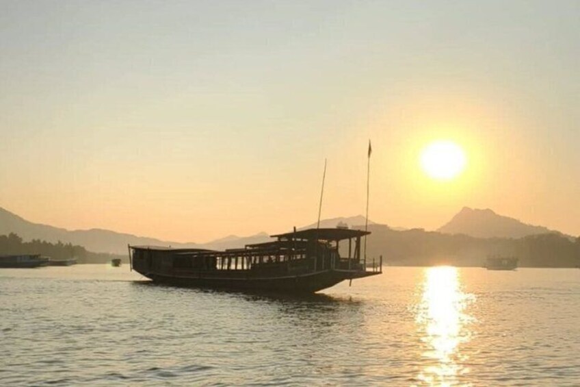 A boat on calm water with a mountain in the background and the sun setting. 5