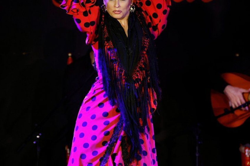 A person wearing a polka dot dress with long sleeves and a black scarf. 2