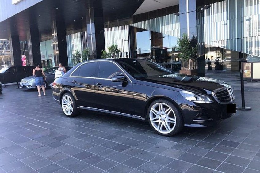 A black car parked in front of a modern building with reflective glass windows. 3
