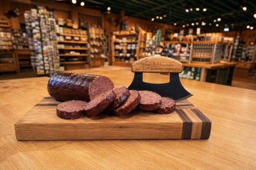 Un affettatrice di carne con una fetta e delle fette su un tagliere di legno in un negozio. 2