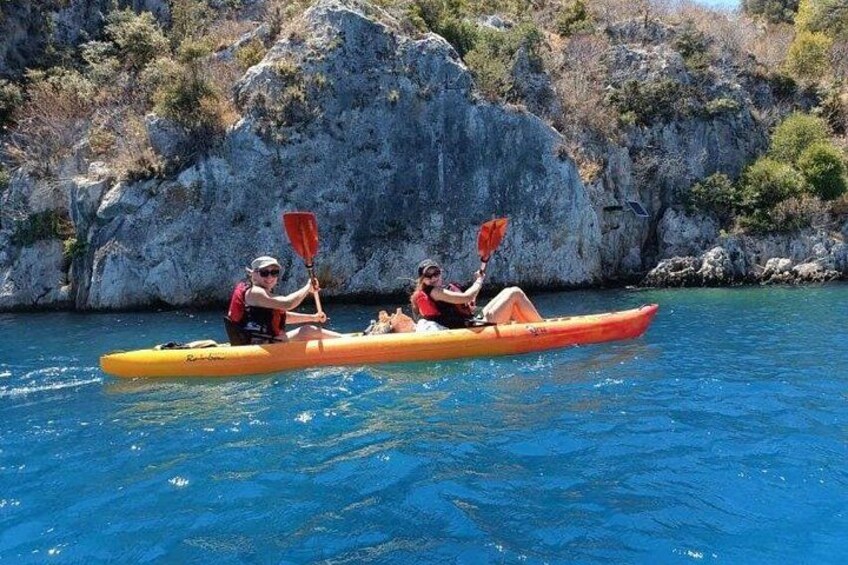 Deux personnes pratiquent le kayak sur une étendue d’eau calme, avec des falaises rocheuses en arrière-plan. 5