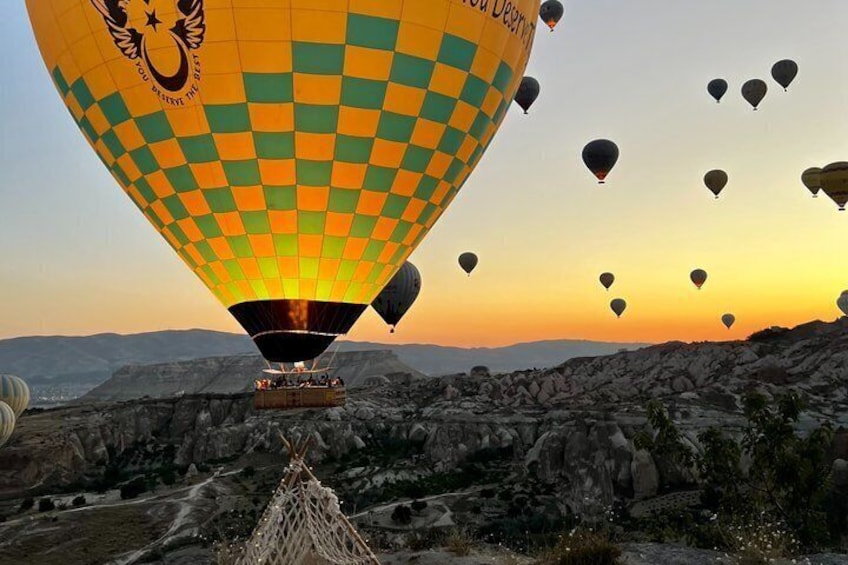 Una mongolfiera con un motivo a scacchi sopra un paesaggio roccioso al tramonto. 4