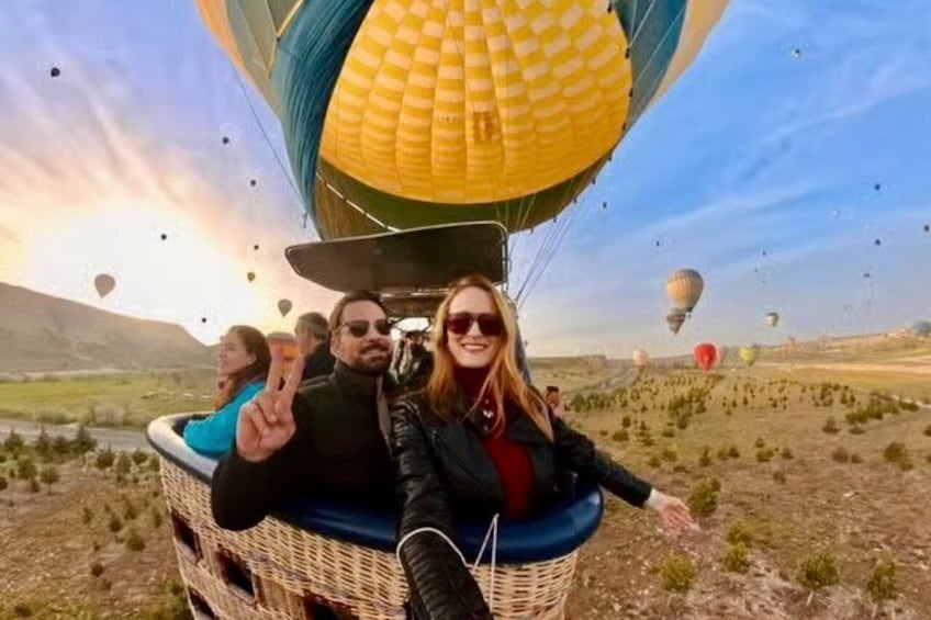 Una mongolfiera con passeggeri, cielo sereno e un paesaggio con vegetazione rada. 1