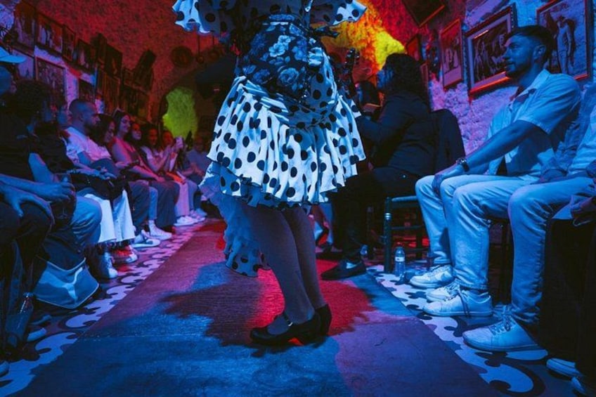 A person walking down a dimly lit hallway with a polka dot dress and a large hat. 3