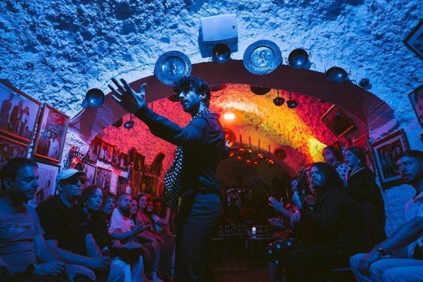 Una persona actuando en un local tenuemente iluminado mientras una multitud observa. 2