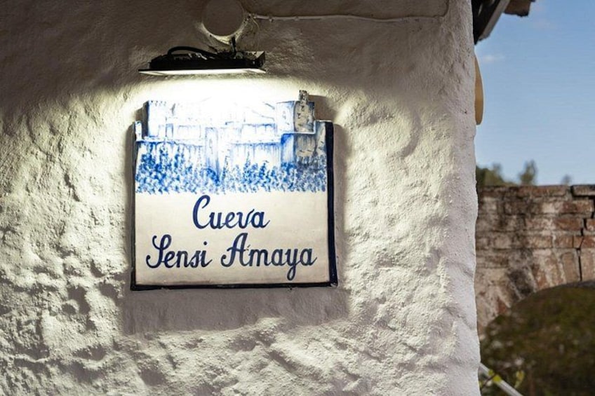 A sign with the text 'Cueva Sensi Amaya' mounted on a white wall. 5