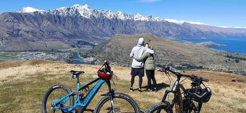 A mountain landscape with snow-capped peaks, a lake, and two bicycles. 2